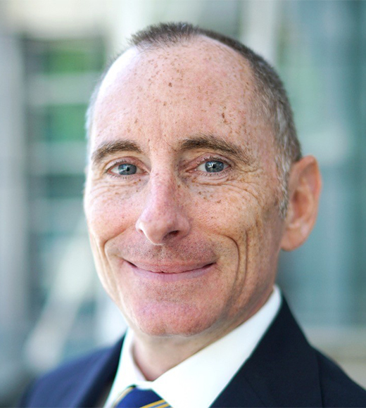 Drew Hambly wearing a suit and smiling at the camera.