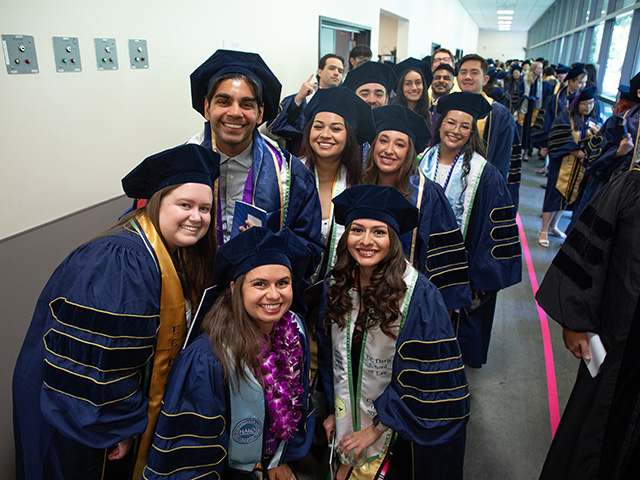 A group of UC Davis Law Class of 2025 graduates smiling at the Mondavi Center.