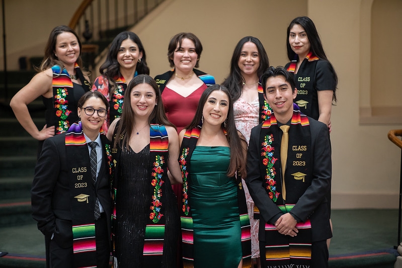 Students wearing graduate stoles gather. 