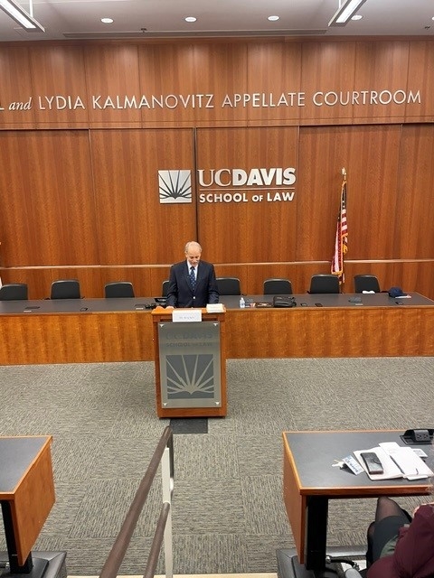 Dr. Gary Solis '72 speaking at the podium at the UC Davis School of Law’s Journal of International Law and Policy symposium.