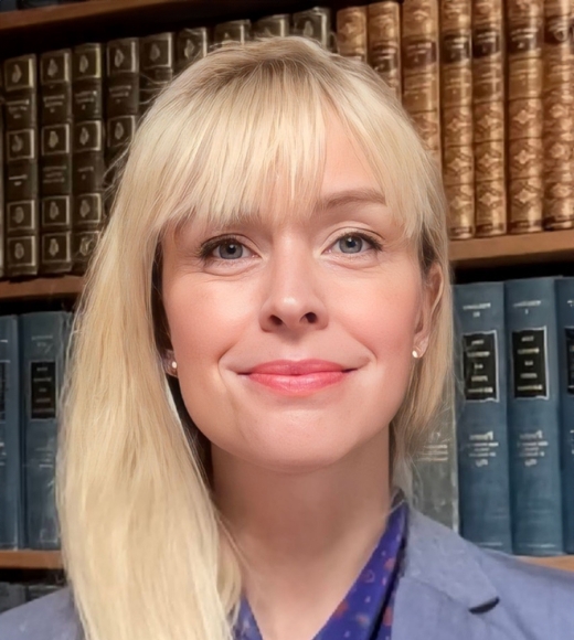 Acting Professor of Law Sarah Polcz wearing a blue blazer and standing in front of a bookshelf.