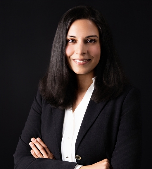 Professor Nila Bala wearing a white blouse and black blazer. She has her arms crossed and is smiling at the camera.
