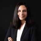 Professor Nila Bala wearing a white blouse and black blazer. She has her arms crossed and is smiling at the camera.
